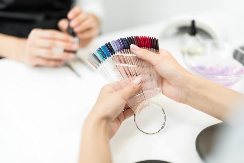 cropped shot of woman choosing nail polish color in beauty salon